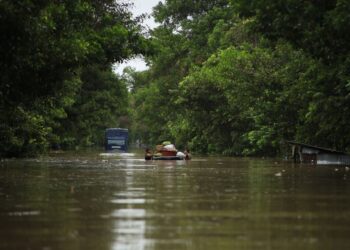 DUA orang penduduk meredah sedalam satu meter sambil menolka pelampung di jalan Pasir Mas-Rantau Panjang Kelantan, semalam-UTUSAN/KAMARUL BISMI KAMARUZAMAN.