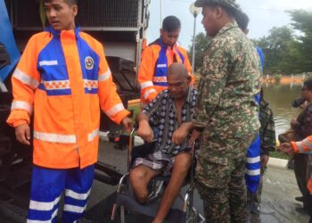 ANGGOTA Angkatan Pertahanan Awam dan tentera membantu memindahkan Nik Man Awang yang uzur di PPS SK Mangkuk, Kuala Nerus, hari ini. - UTUSAN/TENGKU DANISH BAHRI TENGKU YUSOFF