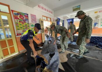 ANGGOTA tentera dan polis berpadu tenaga bergotong-royong membersihkan kawasan yang ditenggelami banjir di Pasir Puteh, Kelantan-UTUSAN/TOREK SULONG.