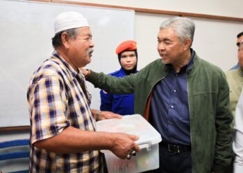 AHMAD Zahid Hamidi (kanan) menyerahkan kit makanan kepada mangsa banjir di PPS SK Jelor, Pasir Puteh, Kelantan hari ini-UTUSAN/KAMARUL BISMI KAMARULZAMAN