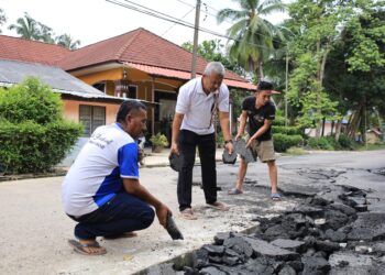 MUHAMMAD Hassan Ibadullah (tengah) bersama penduduk kampung membuang kepingan tar yang masih berada di tengah jalan selepas dihanyutkan arus deras semasa banjir di Kampung Bakong, Pasir Mas, Kelantan-UTUSAN/KAMARUL BISMI  KAMARUZAMAN