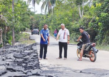 MUHAMMAD Hassan Ibadullah (tengah) bersama penduduk kampung menunjukkan bahagian jalan yang rosak akibat arus deras semasa banjir di Kampung Bakong, Pasir Mas, Kelantan. – UTUSAN/KAMARUL BISMI  KAMARUZAMAN.