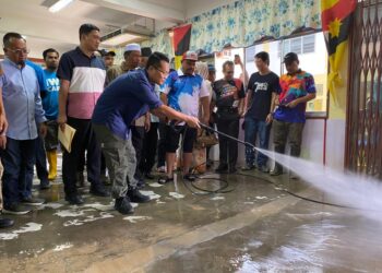 NIK Nazmi Nik Ahmad (depan) membersihkan bilik darjah yang ditenggelami banjir di SK Bendang Pa' Yong, Tumpat, Kelantan-UTUSAN/YATIMIN ABDULLAH.