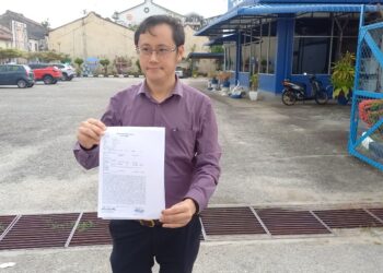 JAMES Khoo menunjukkan laporan yang dibuat di Balai Polis Tengkera, Melaka. - UTUSAN/AMRAN MULUP