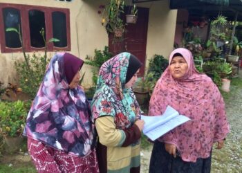 WAN Maimun Wan Sarif (kanan) meneliti notis arahan mahkamah untuk mengosongkan kediaman di Kampung Pulau Sekati, Kuala Terengganu, semalam– UTUSAN/TENGKU DANISH BAHRI TENGKU YUSOFF.