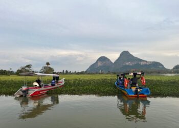 PENGUNJUNG menikmati keindahan Bukit Cabang dengan berlatar belakangkan tumbuhan cantik di permukaan air sewaktu berkunjung ke Tasik Timah Tasoh, Perlis. – UTUSAN/ASYRAF MUHAMMAD