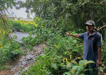SALEH Jaratin menunjukkan air parit di belakang rumahnya yang berwarna hitam dan mengeluarkan bau busuk serta meloyakan di Kampung Kadir, Nilai UTUSAN/ NOR SHAFAWATI YUP.