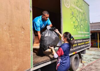 SEORANG ahli 3R Rangers (kanan) SMK Munshi Abdullah di Batu Berendam, Melaka menyerahkan barang-barang kitar semula yang telah diasingkan kepada kakitangan SWM. - UTUSAN/MUHAMMAD SHAHIZAM TAZALI