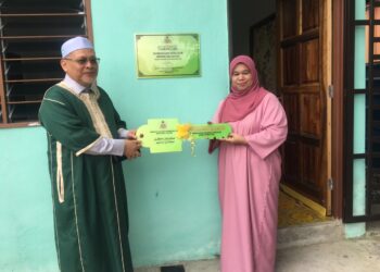 MOHD Amar Nik Abdullah (kiri) menyampaikan replika kunci rumah kepada penerima pada Majlis Penyampaian Cek Sumbangan kepada Masjid Al-Alaq dan Perasmian Rumah Dhuafa' di Kampung Pak Kemek, Panji, Kelantan.-UTUSAN/ ROSMIZAN RESDI