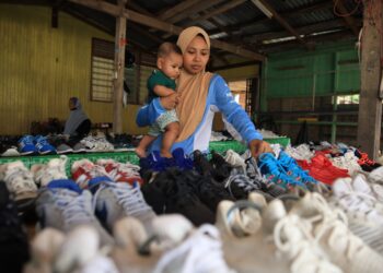 NADZIRAH Kamaruzzaman membetulkan susunan kasut yang disusun dihadapan rumahnya di Kampung Kubang Kual, Rantau Panjang, Kelantan-UTUSAN/KAMARUL BISMI KAMARUZAMAN