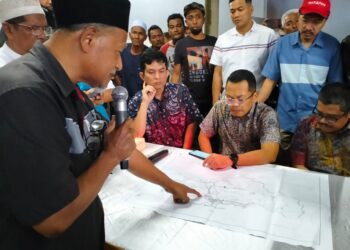 NIK Nazmi Nik Ahmad (duduk tengah) melihat lakaran pembinaan PLSB yang dibentangkan oleh Penasihat Teknikal Jawatankuasa Banjir Rantau Panjang Dr. Mohd. Yazid Abdullah di Kampung Tersang, Rantau Panjang, Kelantan-UTUSAN/ROHANA ISMAIL.