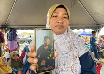 ROSLIZA Mat Yusoff menunjukkan gambar Muhamad Hisyamuddin yang masih hilang selepas bot yang dinaikinya tenggelam di Sungai Kelantan dekat Kampung Paloh Rawa, Machang, Kelantan-UTUSAN/ROHANA MOHD. NAWI