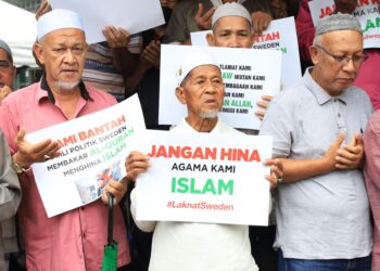 SEORANG warga emas memang kad tertera tulisan Jangan Hina Agama Islam pada bantahan aman tindakan membakar Al-Quran.-UTUSAN/KAMARUL BISMI KAMARUZAMAN