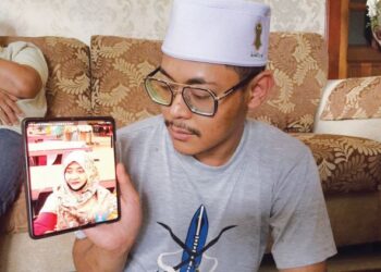MUHAMMAD Harith Mustaqim menunjukkan gambar Zarina Mukhtar di Kampung Sungai Rengas, Kuala Terengganu, semalam. 
– UTUSAN/TENGKU DANISH BAHRI TENGKU YUSOFF