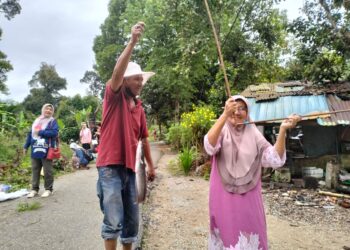 ZUBAIDAH Ismail (kanan) teruja berjaya menaikkan ikan keli walaupun batang pancing diperbuat daripada pelepah salaknya patah ketika menyertai pertandingan di tali air Kampung Perangkap, Pasir Mas, Kelantan-UTUSAN/ROHANA ISMAIL.
