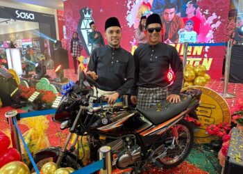 ZUL Huzaimy (kanan) bersama Murtadhatumizi Mustapha menunjukkan motosikal Yamaha RXZ Catalyzer yang menjadi hadiah cabutan bertuah semasa Majlis Pelancaran Baju Melayu Intan Berlian Exclusive di KB Mall, Kota Bharu, Kelantan hari ini-UTUSAN/ROSMIZAN RESDI