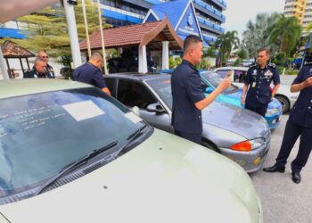 MUHAMAD Zaki Harun (kanan) memeriksa sebahagian kereta jenis Proton Wira yang dirampas selepas menahan tujuh suspek di Kota Bharu,Kelantan-UTUSAN/ROHANA MOHD.NAWI.