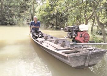 SEORANG penduduk, Din menggunakan bot selepas rumah ditenggelami banjir di Kampung Tersang Rantau Panjang, Kelantan. – UTUSAN/ROHANA ISMAIL