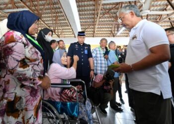 AL-SULTAN ABDULLAH Ri'ayatuddin Al-Mustafa Billah Shah (kanan) bercemar duli menyantuni mangsa banjir di Pusat Pemindahan Sementara (PPS), di Taman Guru di Kuantan, Pahang. - FOTO/SHAIKH AHMAD RAZIF