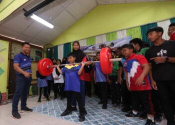 AHMAD JANIUS Abdullah melihat seorang pelajar mengangkat bebanan pada Program Pencarian Bakat Sukan Angkat Berat di SK Kesang Tua, Jasin, Melaka. - UTUSAN/AMRAN MULUP