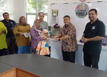 RAIS Yasin menyampaikan sumbangan persekolahan kepada Wartawan Sinar Harian, Farhana Yaacob pada Majlis Penyerahan Sumbangan Kelab Pendika di RUTC, Klebang, Pulau Gadong, Melaka. - UTUSAN/AMRAN MULUP