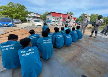 SYED Nur Adli Syed Ab. Rahman (berdiri, tengah) bersama 13 nelayan asing Vietnam di Pangkalan Operasi Maritim Malaysia Kelantan, Tok Bali, Pasir Puteh, Kelantan, hari ini. UTUSAN/TOREK SULONG