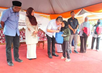 SALAHUDDIN Ayub menyampaikan beg sekolah kepada seorang murid pada Majlis Sumbangan Kembali Ke Sekolah dan Program KPDN di Pusat Peduli Rakyat DUN Kota Siputeh di Kampung Kandis, Kodiang.