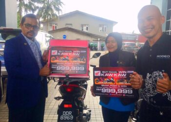 ADNAN Mat (kiri ) menampalkan pelekat kepada kenderaan perkhidmatan e-hailing di Pejabat Perkeso Negeri Kelantan hari ini. UTUSAN/ ROSMIZAN RESDI
