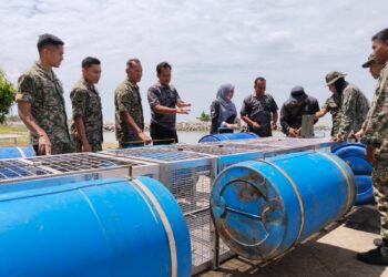 MOHD. FIRRDHAUS Mahmood (empat dari kiri) menerangkan fungsi sangkar kepada anggota ATM yang terlibat operasi menangkap dan memindahkan buaya di pesisir Pantai Tanjung Bidara dan Kuala Linggi, Masjid Tanah, Melaka. - UTUSAN/MUHAMMAD SHAHIZAM TAZALI