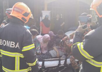 ANGGOTA bomba dan orang ramai memberikan bantuan kepada Siti Aisyah yang sesak nafas selepas melihat rumahnya di Taman Ria Jaya di sini terbakar pagi tadi. -UTUSAN/OTHMAN YAHAYA