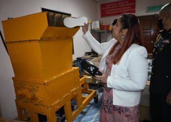 NORENA Jaafar memasukkan kasut ke dalam mesin untuk dilupuskan pada program pelupusan eksibit di Stor KPDN, Krubong, Melaka. - UTUSAN/MUHAMMAD SHAHIZAM TAZALI