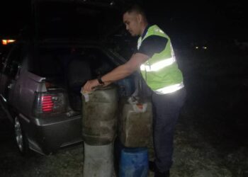 ANGGOTA penguat kuasa KPDN Kelantan memeriksa minyak diesel yang dirampas dalam serbuan di Bachok, Kelantan semalam.-UTUSAN/IHSAN KPDN KELANTAN