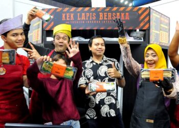 AIZAT ISHAK (tengah) dan Julia Amani serta pekerjanya menunjukkan pelbagai kek lapis yang dijual sempena Festival Makanan Antarabangsa Johor dan Muzik Nusantara 2023 di Stadium Tertutup Majlis Bandaraya Pasir Gudang.