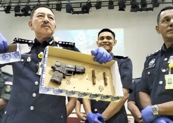MUHAMAD Zaki Harun (kiri) menunjukkan pistol yang dirampas dalam serbuan di Kampung Gong Datuk, Pasir Puteh, Kelantan semalam-UTUSAN/ROHANA ISMAIL
