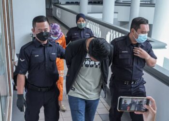 KEDUA tertuduh diiring keluar anggota polis selepas mengaku tidak bersalah di Mahkamah Majistret, Ayer Keroh, Melaka atas pertuduhan mencuri barang kemas keluarga pesakitnya bernilai RM12,000. - UTUSAN/SYAFEEQ AHMAD