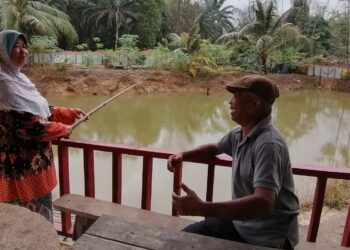 MAMAT Ali menemani isteri, Khatijah Hamid  memancing di kolam pancing dibina belakang rumah di Kampung Belukar Bukit, Hulu Terengganu. – UTUSAN/NOOR HAYATI MAMAT