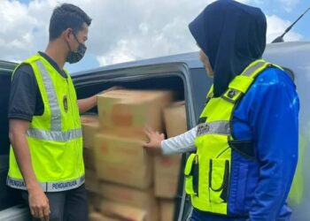 DUA anggota penguat kuasa KPDN Kelantan menunjukkan minyak masak peket yang dirampas selepas menahan sebuah MPV di Kota Kubang Labu, Wakaf Bharu, Kelantan semalam.-UTUSAN/IHSAN KPDN KELANTAN