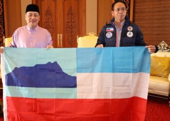 HAJIJI Noor (kiri) menyerahkan bendera Sabah kepada Dr. Justin Sentian di Menara Kinabalu di Kota Kinabalu hari ini.