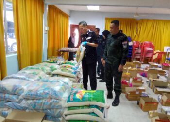 AMRAN Dolah (kiri) bersama pegawai Pasukan Gerakan Am menunjukkan beras Siam yang dirampas dalam Operasi Bersepadu di Tumpat, Kelantan hari ini-UTUSAN/ROHANA MOHD.NAWI.