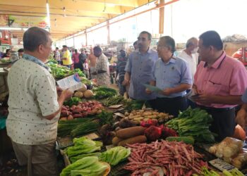 NUR Mohammad Bakhtir (tiga dari kanan) bersama Seh Yong (tengah) memberi penerangan tentang manfaat caruman SKSPS kepada peniaga sayur di Pasar Besar Seremban hari ini.-UTUSAN/NOR SHAFAWATI YUP.