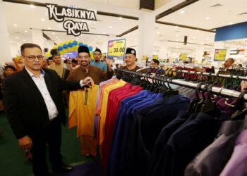 AZMAN Ismail (kiri) sedang melihat koleksi pakaian raya yang dijual pada harga rendah pada Majlis Pelancaran Klasik Riang Raya di Mydin Mall, Kota Bharu, Kelantan, hari ini. UTUSAN/ROSMIZAN RESDI