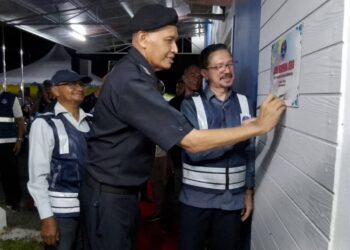 MIT Emong (kiri) menandatangani plak sempena perasmian Pusat Rukun Tetangga Mukim Dusun Rendah, Kota Bharu, Kelantan semalam.-UTUSAN/ROHANA MOHD.NAWI
