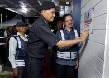 MIT Emong (kiri) menandatangani plak sempena perasmian Pusat Rukun Tetangga Mukim Dusun Rendah, Kota Bharu, Kelantan semalam.-UTUSAN/ROHANA MOHD.NAWI