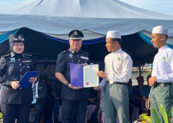 AHMAD Faqih Syazani Mohd. Zainal (kanan) dan rakannya, Muhammad Alwi Mustafa Kamal menerima surat penghargaan daripada Sik Choon Foo di perkarangan IPD Gua Musang, Kelantan hari ini.UTUSAN/AIMUNI TUAN LAH