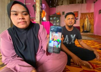 NUR Ain Nabihah Mohd. Zamri (kiri) menunjukkan gambar anaknya Muhammad Azim yang maut terjatuh ke dalam lubang kumbahan semasa ditemui pemberita di rumahnya di Lorong Pondok Haji Muhammad, Selisig, Pasir Puteh, Kelantan hari ini-UTUSAN/YATIMIN ABDULLAH