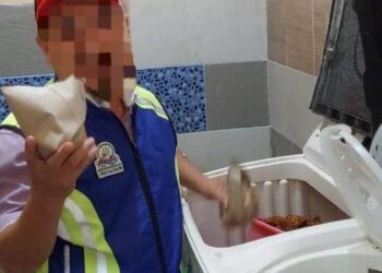 ANGGOTA penguat kuasa Majlis Daerah Bachok menunjukkan nasi bungkus yang ditemui dalam mesin basuh semasa menjalankan serbuan di sebuah rumah di Tangok, Bachok, Kelantan semalam.-UTUSAN/IHSAN MAJLIS DAERAH BACHOK