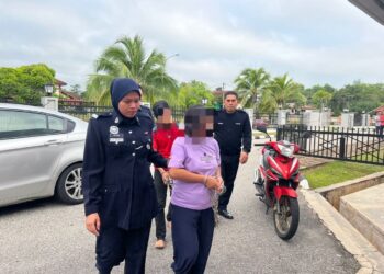 TERTUDUH Sherly Gutterrez (dua kiri) dan Aliuddin Abdul Aziz (belakang) diiringi oleh anggota polis ke Mahkamah Sesyen Gua Musang, Kelantan hari ini-UTUSAN/AIMUNI TUAN LAH