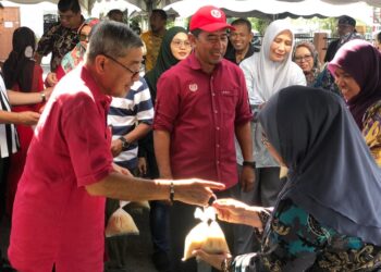 AHMAD Bashah Md. Hanipah (kiri) bersama Zamri Yusuf mengedarkan bubur lambuk kepada penduduk di Taman Wira, Mergong di Alor Setar.