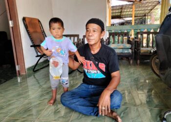 MAT NOH Mohamad (kanan) bersama anaknya, Mohd. Adam yang mengalami sakit usus di Felda Kota Gelanggi 4 di Jerantut, Pahang. - UTUSAN/HARIS FADILAH AHMAD