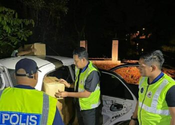 ANGGOTA KPDN Kelantan (kanan) dan Polis membuat pemeriksaan keatas sebuah kereta yang ditahan selepas menyeludup minyak masak peket di Kampung Telaga Bata, Tumpat, Kelantan semalam.-UTUSAN/IHSAN KDPN KELANTAN